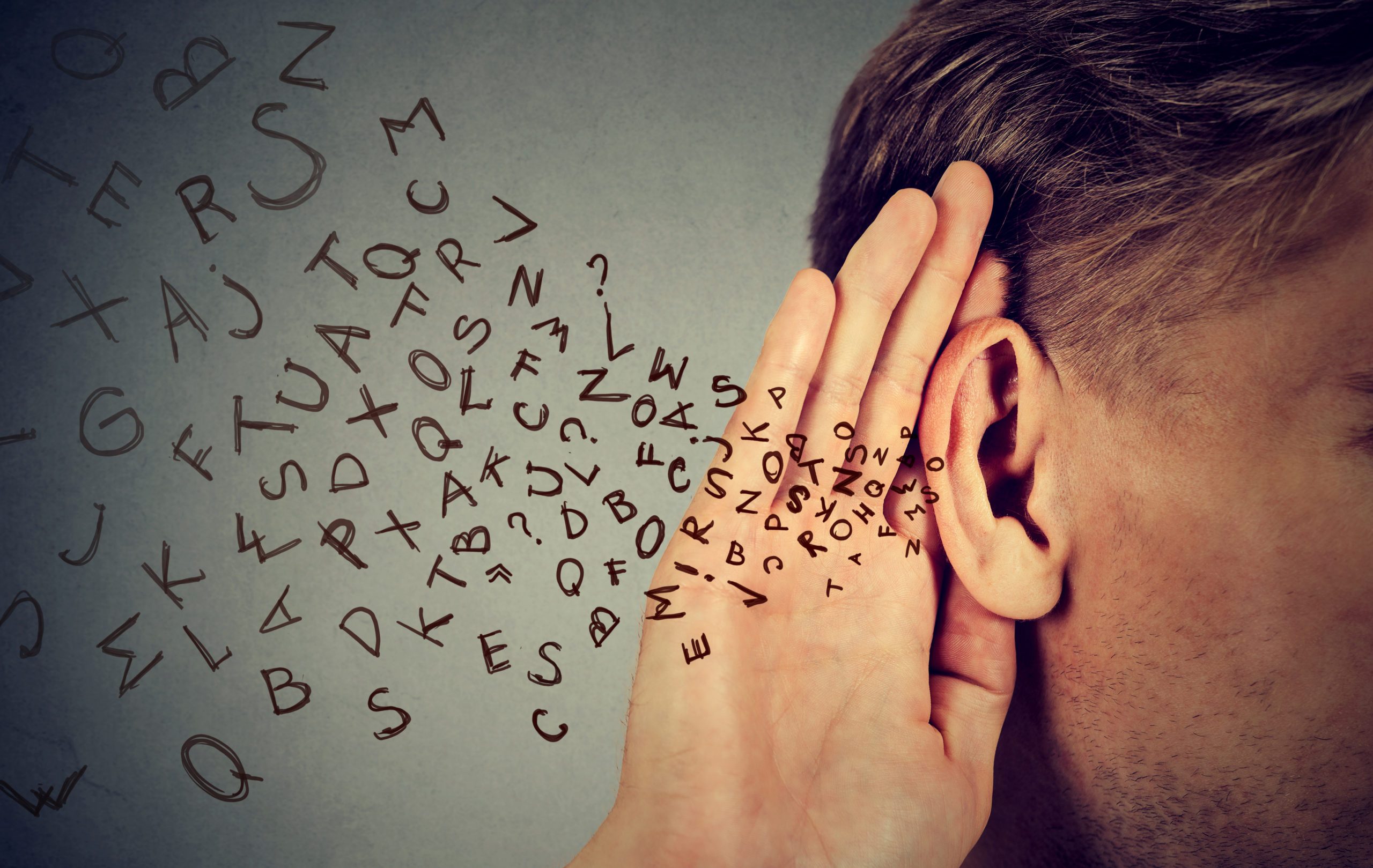man holds hand near ear listens carefully alphabet letters flying in