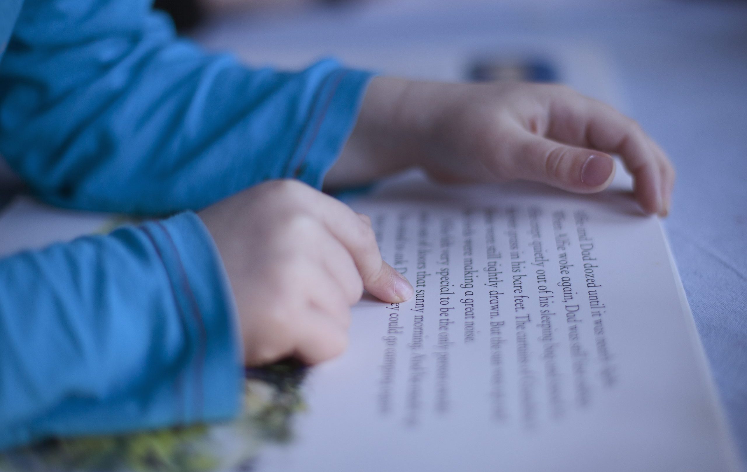 close up boys fingers pointing to words in book