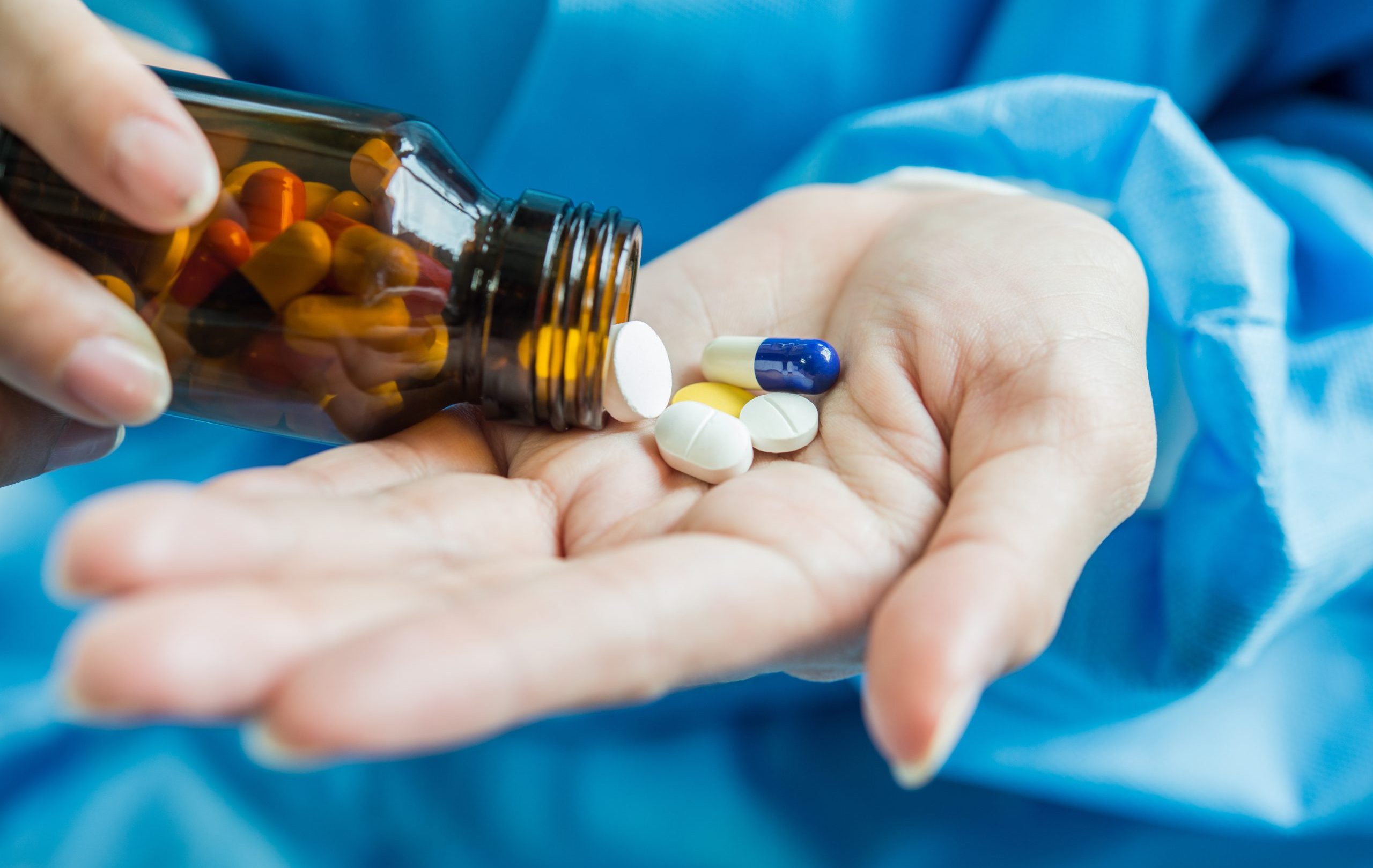 Woman's hand pours the medicine pills out of the bottle